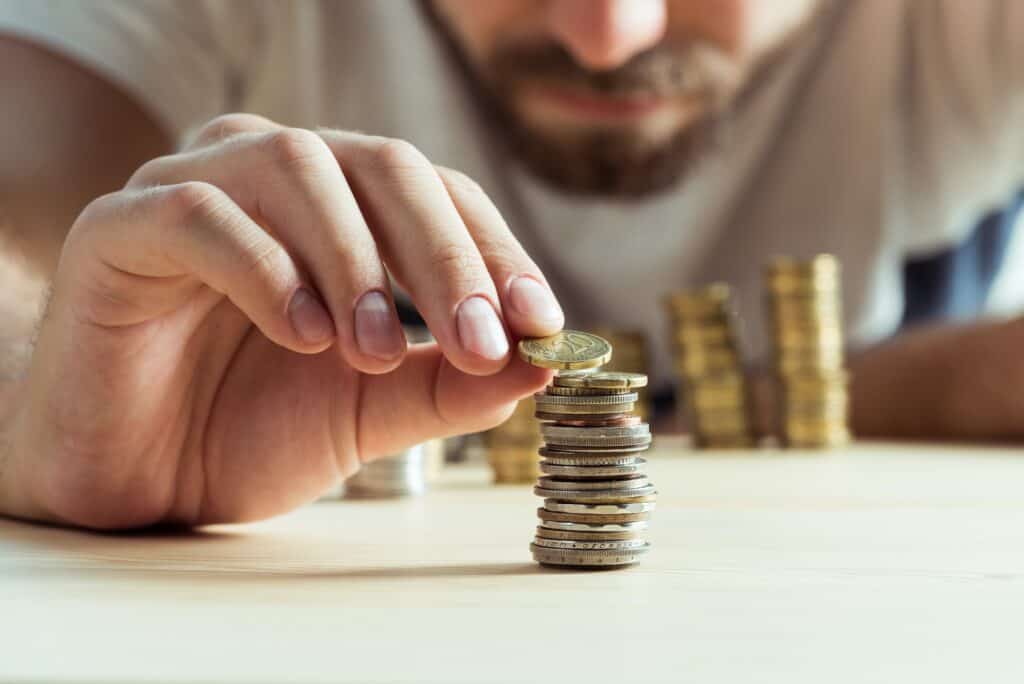 cropped view of man stacking coins on table, investment concept