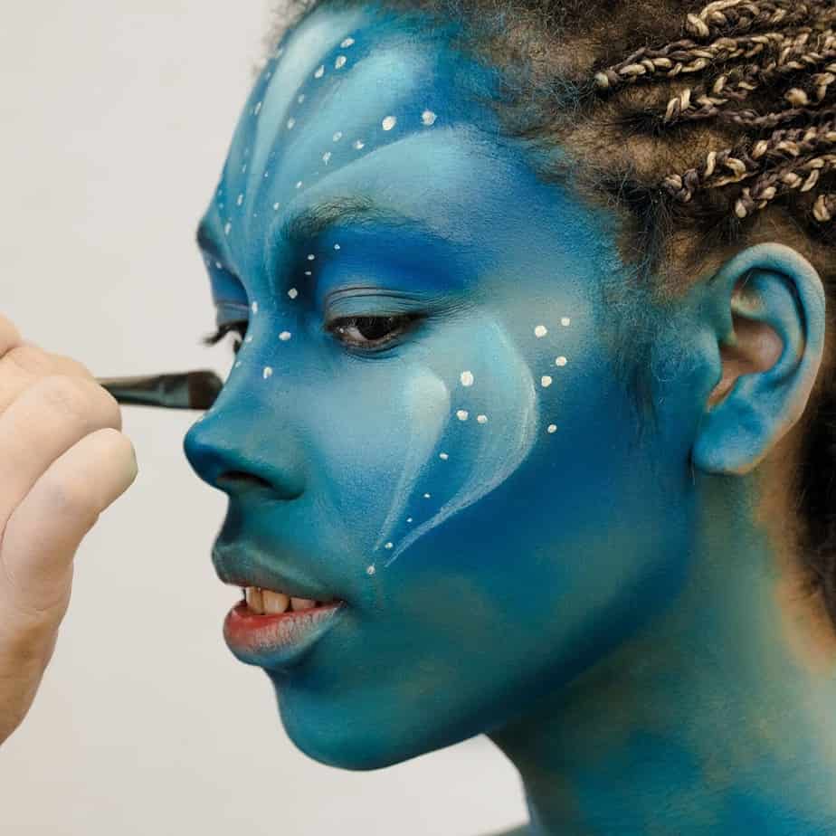 Makeup Artist applies ye shadows to a beautiful woman in Avatar style